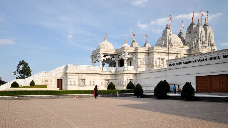 Side view of Swaminarayan Sanstha temple against cloudless blue sky.